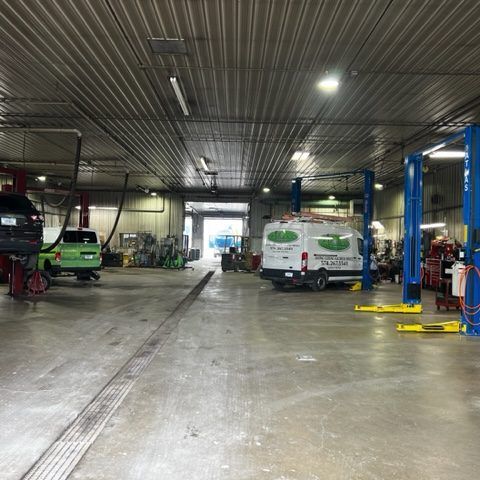 Inside the R&G service bay with vehicles on lifts and a service van parked in the aisle
